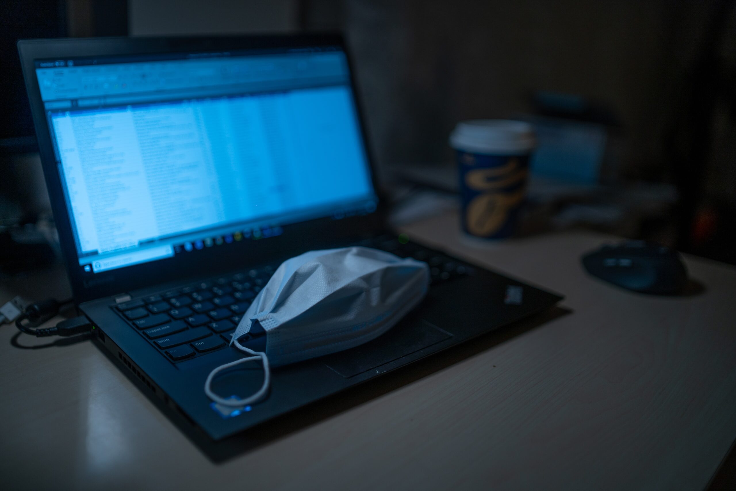 black laptop computer beside black framed eyeglasses on brown wooden table