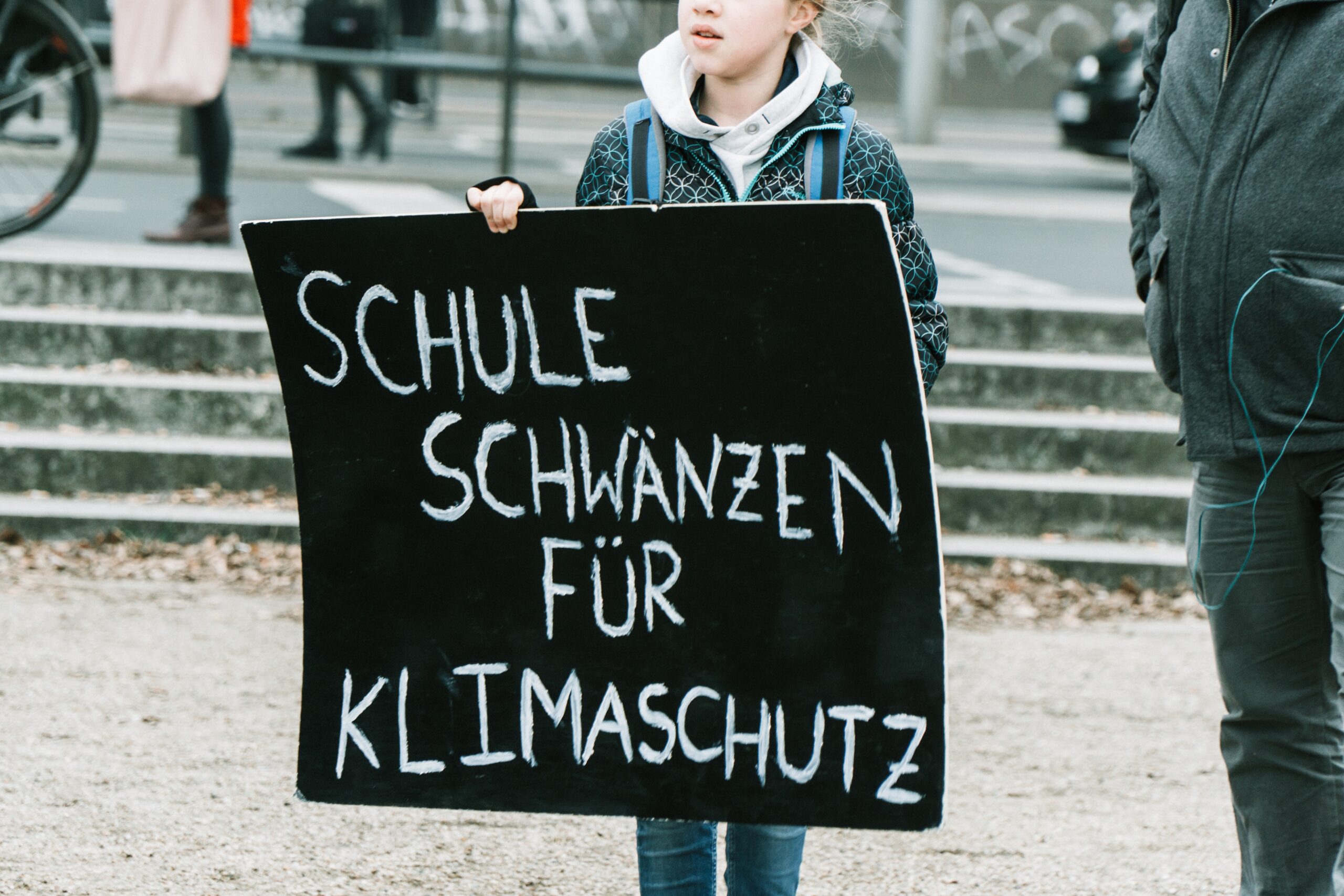 woman holding black and white welcome to the beach signage